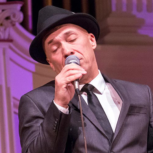 Frank Sinatra tribute singer performing into a microphone.